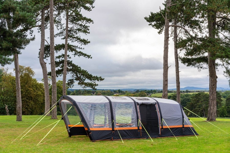 An image of the OLPRO Blakedown Breeze 4 Berth Inflatable Tent pitched on a campsite with a treeline in the background.