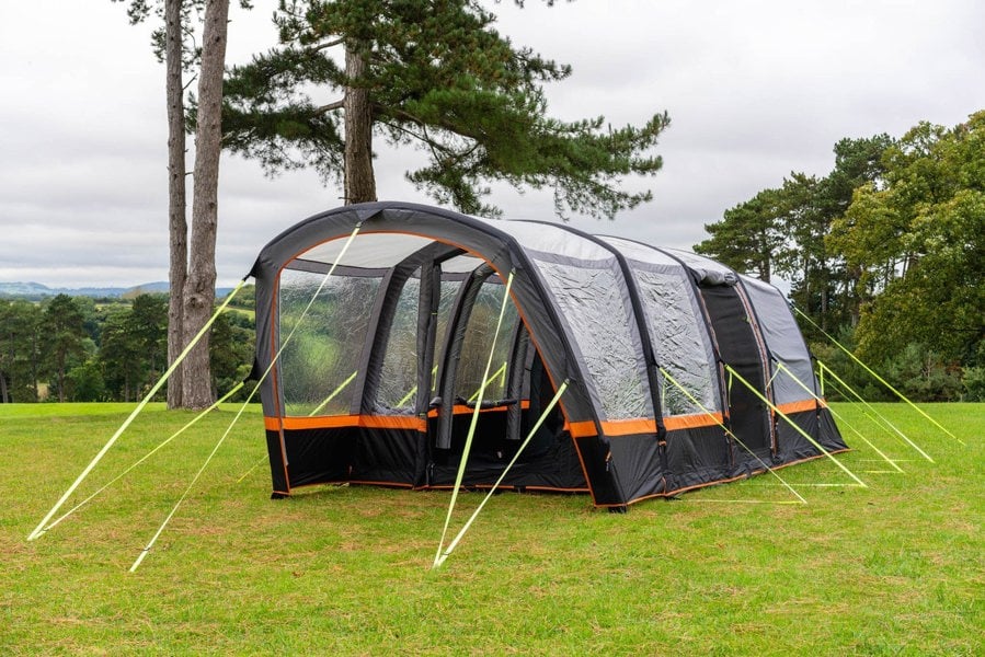 An image of the OLPRO Blakedown Breeze 4 Berth Inflatable Tent pitched on a campsite with a treeline in the background.