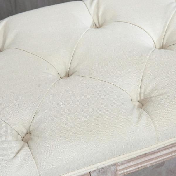 Cream upholstered tufted seat cushion on a 2-tier storage bench