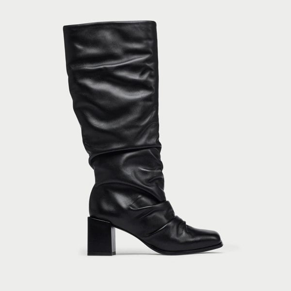 Black knee-high boot on a light gray background