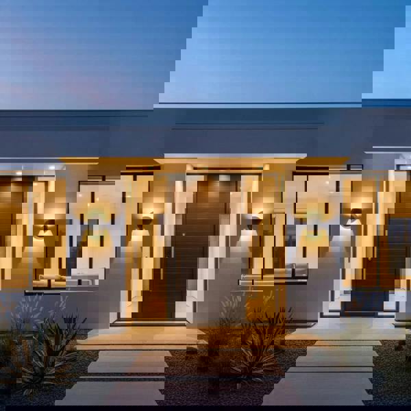 black modern outdoor wall lamp mounted either side of the front door of a modern home with a wooden door 