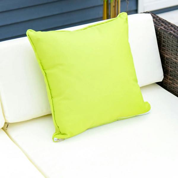 Cream cushion with lime green throw pillow on brown rattan sofa