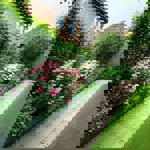 Grey metal raised garden bed bordering a stone-paved walkway.