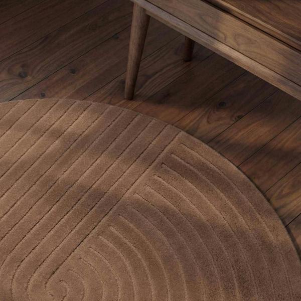 Brown textured rug on a wooden floor with a wooden side table.