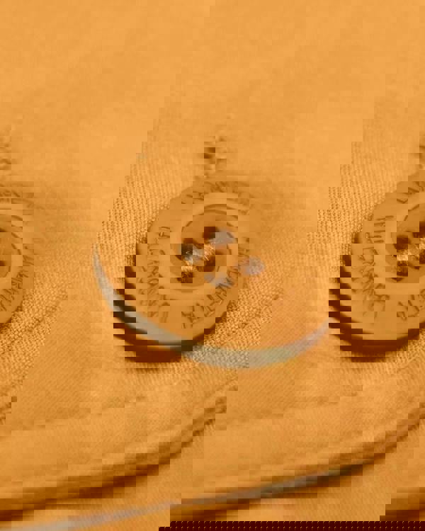 Lambretta Mens Showerproof Classic Harrington MOD Scooter Jacket Coat, close-up of a white button with 'Lambretta' engraved around the edge, sewn onto beige fabric.