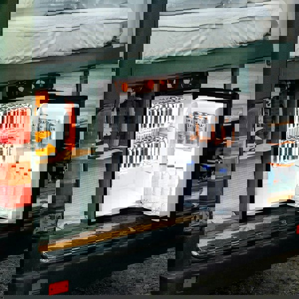 Compact 3-way absorption fridge with a sleek black exterior, featuring clear shelves holding cans and bottles, ideal for camping or travel