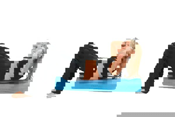 Woman foam rolling her back using a Fitness Mad Foam Roller 90cm