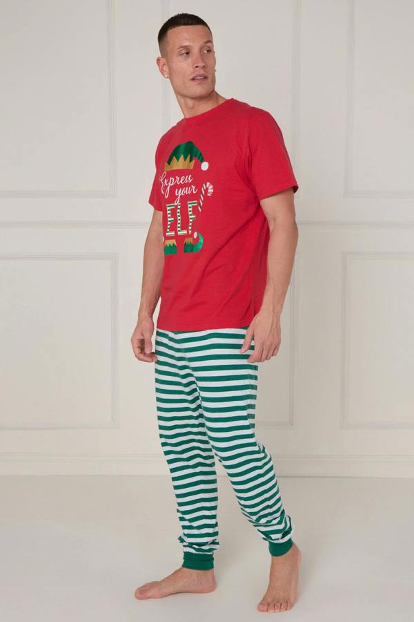 Man wearing a red t-shirt with a Christmas design and green and white striped pants on a white background