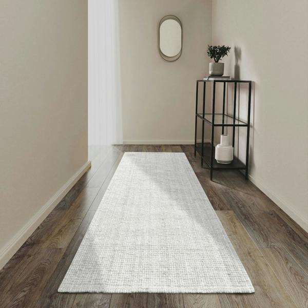 White runner rug on a wooden floor with a side table and mirror in the background.