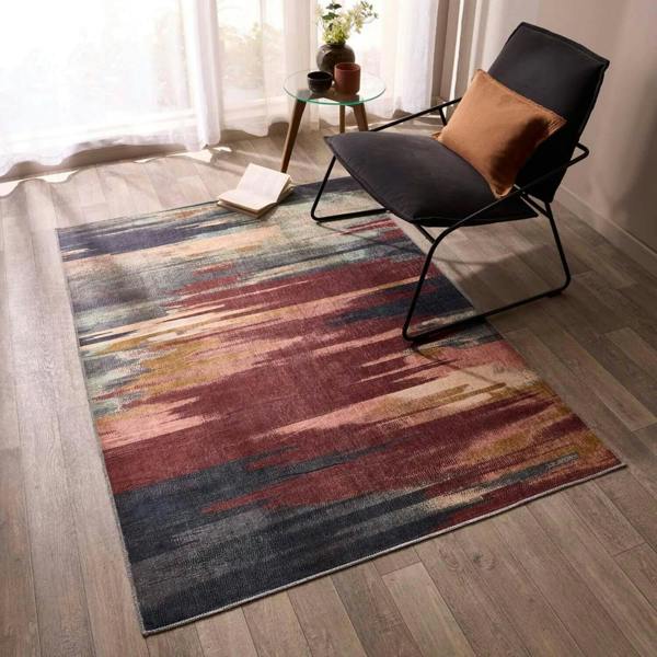 Multicolored abstract patterned rug on a wooden floor with a modern chair.