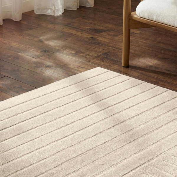 Beige rug on a wooden floor with a chair partially visible