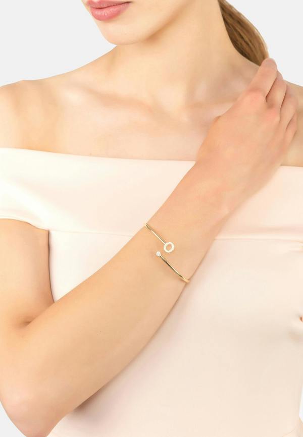 Gold bracelet on a person's wrist with a plain background