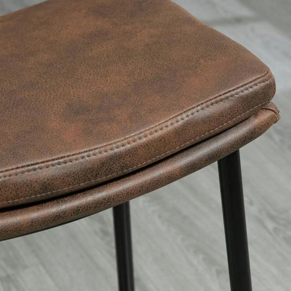 Brown upholstered bar stool seat edge with stitched piping and black steel legs
