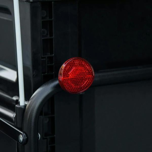 Red round reflector on the black bicycle cargo trailer frame for enhanced visibility