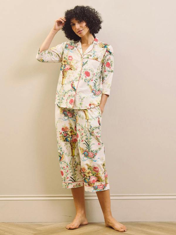 Woman wearing a floral capri pyjama set against a plain background