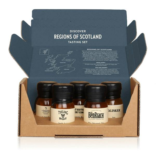 A whisky tasting set in an open cardboard box, featuring five small miniature bottles of single malt Scotch whisky from different regions. The inside of the box lid displays a map of Scotland highlighting the whisky regions (Islay/Campbeltown, Speyside, Highland, Lowland) and text describing the regions and tasting notes. The bottles shown are from brands including The Singleton, Teeling, The Benriach, and Talisker.
