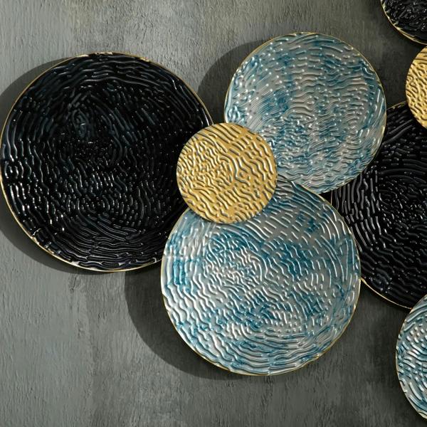 Close-up of three textured metal discs in black and blue with a gold accent disc