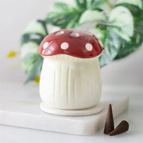 Mushroom incense cone holder with red cap and cream base; brown incense cones beside it