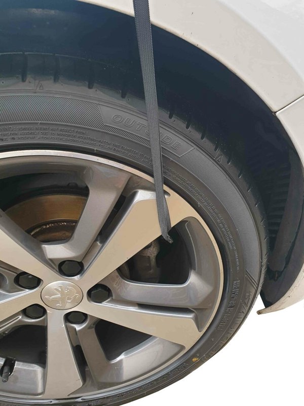 The Nylon Car Top Cover Extra Large by OLPRO on a white family car depicting the hooks and strap that are hooked around the alloy of the vehicle.