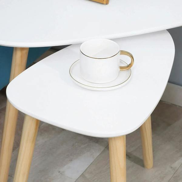 Close-up of white oval tabletop with stacked cups on a nesting side table