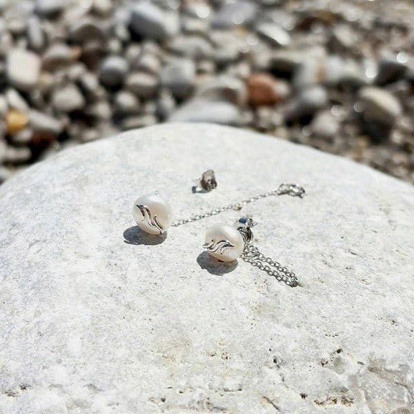 Pearl chain earrings on a rock.