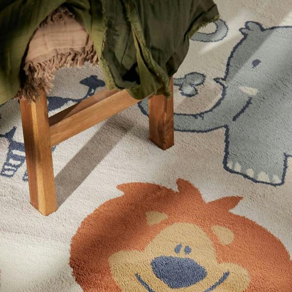 Children's rug with lion design featuring a wooden stool and green fabric.