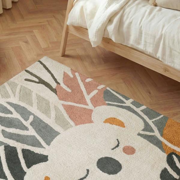 Decorative rug with a cartoon character on a wooden floor next to a bed.