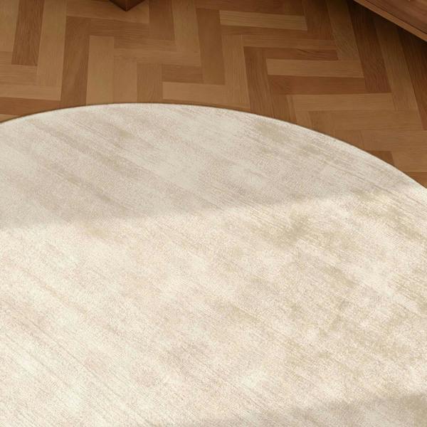 Round beige rug on a wooden floor
