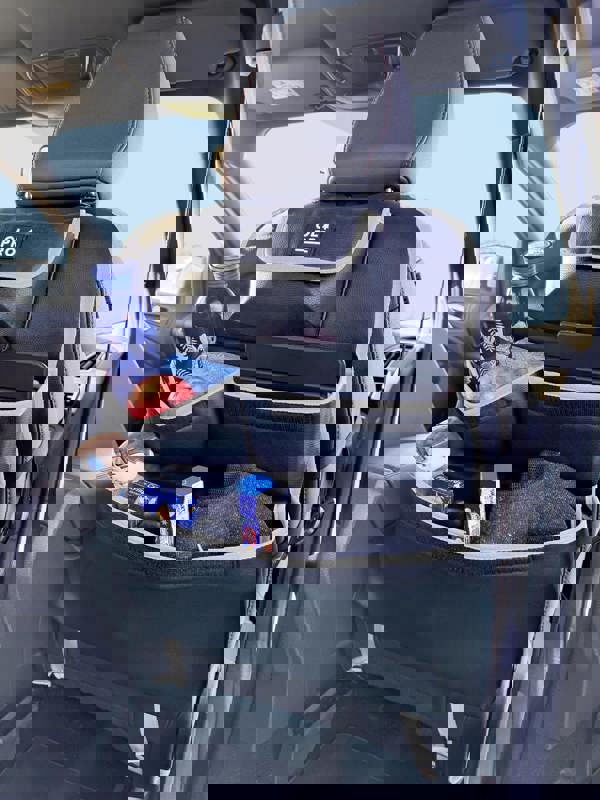 The Rear Single Seat Storage Organiser in Grey by OLPRO being fitted onto the rear of the passenger seat of VW vehicle with some products for children stored in it.