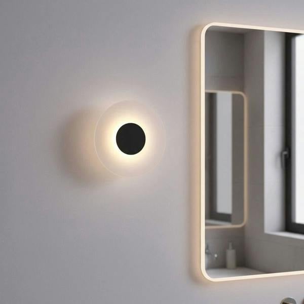 black bath sconce light mounted on the wall next to a bathroom mirror