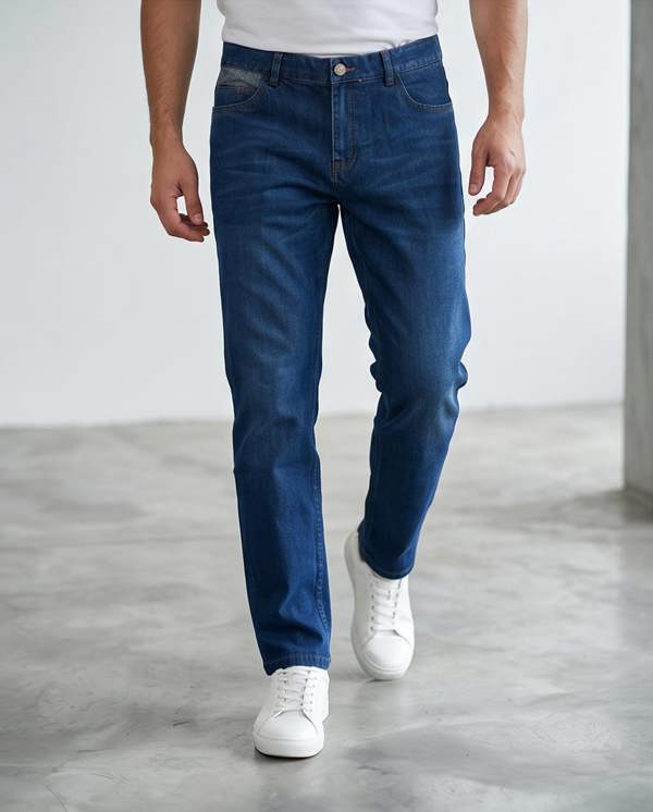 Person wearing blue jeans and white sneakers on a plain background