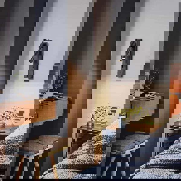 black wall mounted reading light with USB port mounted on a white wall next to a bed in a bedroom