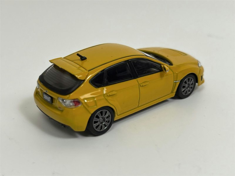 a yellow toy car on a white surface