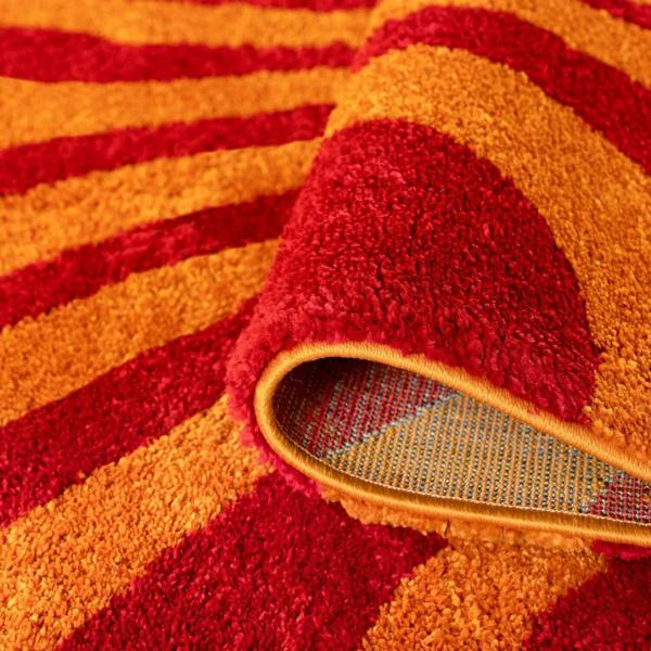 Close-up of a red and orange textured rug with a metallic backing.