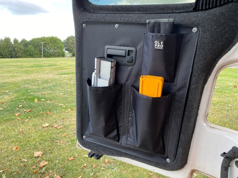 An image of the left hand side of the VW T5/T6 Barn Door Storage Organiser from OLPRO with items stowed inside of it.