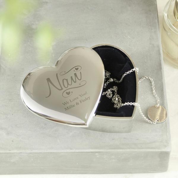 A silver heart-shaped trinket box by Abode Home & Gifts, resting on a rustic grey concrete block with the lid slid slightly open to show the dark lining and a silver chain. The lid is custom engraved with "Nan We Love You! Millie & Finley".