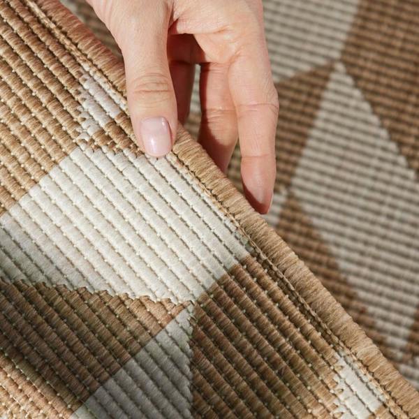 Close-up of a hand touching a textured brown and beige fabric