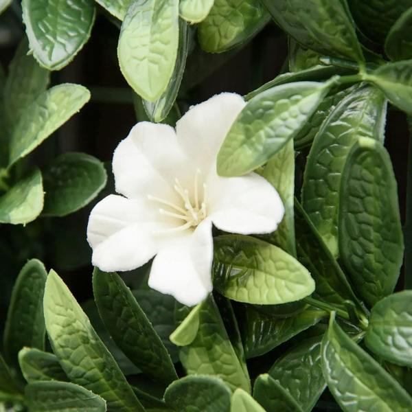 Close-up of white rhododendron flower on textured green artificial leaves