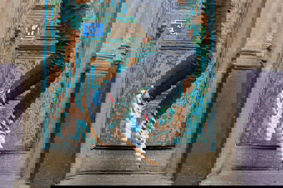 Person in blue jeans, varsity striped socks and white sneakers jumping in front of a textured door with peeling paint.