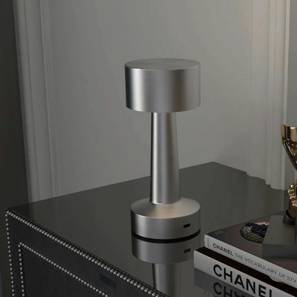 Silver table lamp with tall pillar and cylindrical shade; touch button on round base