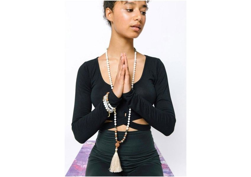 Woman wearing Selene purity mala bracelet and necklace by Kati Kaia while meditating in black outfit
