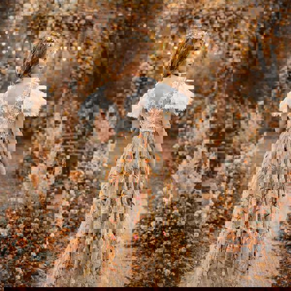 Young girl in a floral dress standing in a decorated garden with flowers and lights.