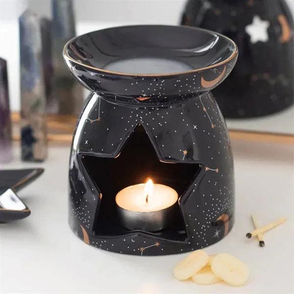 Constellation oil burner with cut-out front, black ceramic and lit candle in dish