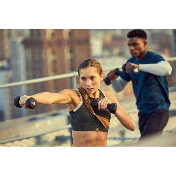Woman exercising with dumbbells on a rooftop with a blurred cityscape background
