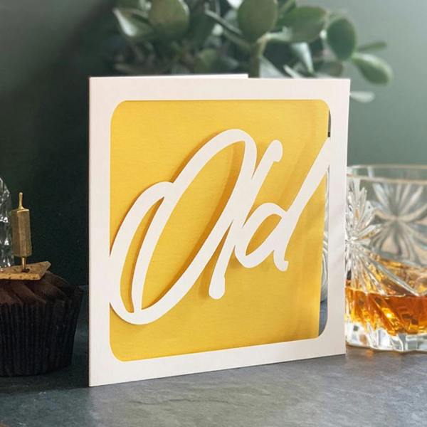 Square white papercut birthday card featuring the word Old with a bright yellow paper insert
