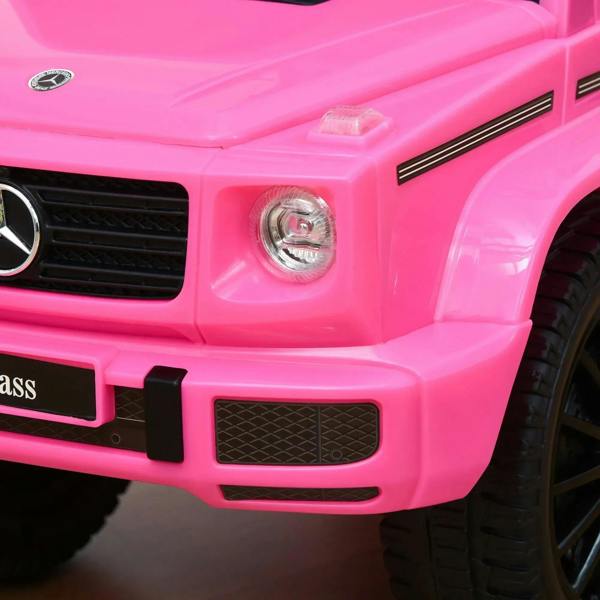 Pink ride-on car front with headlight, grille, and bumper detail, black wheels partly visible.