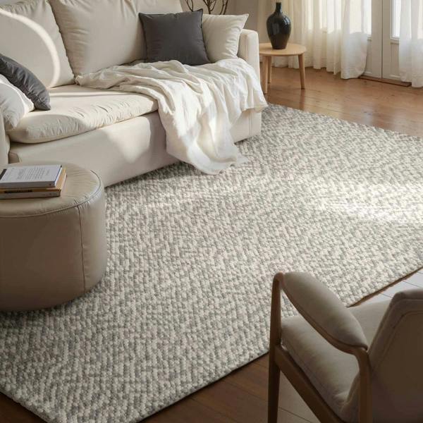 Living room with a beige sectional sofa, ottoman, and chair on a textured rug.