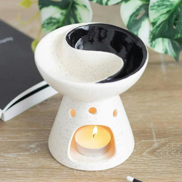 Ceramic yin-yang oil burner in speckled white with black dish; tealight flame inside