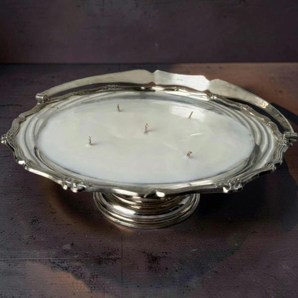 Silver platter with a candle inside on a dark surface