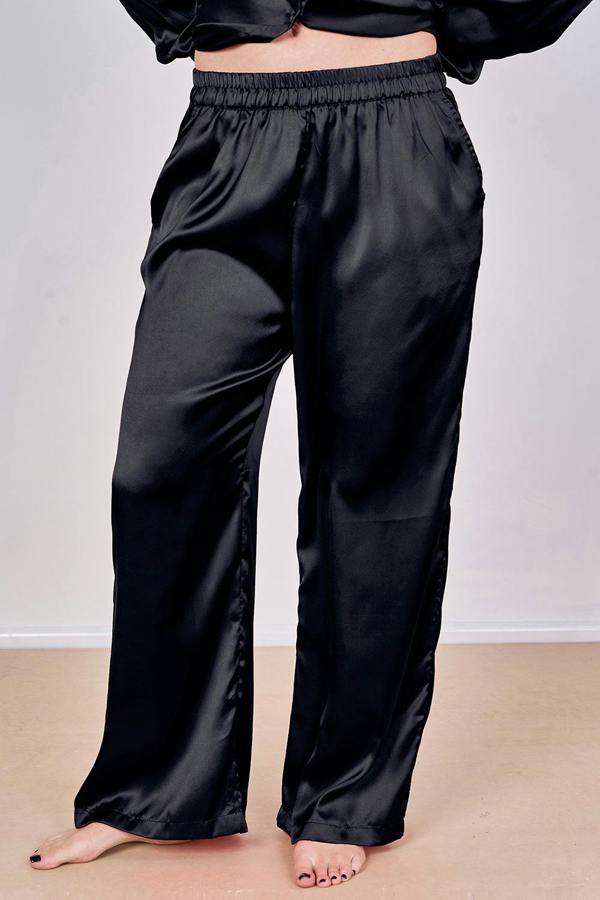 Black satin pants worn by a person on a plain background